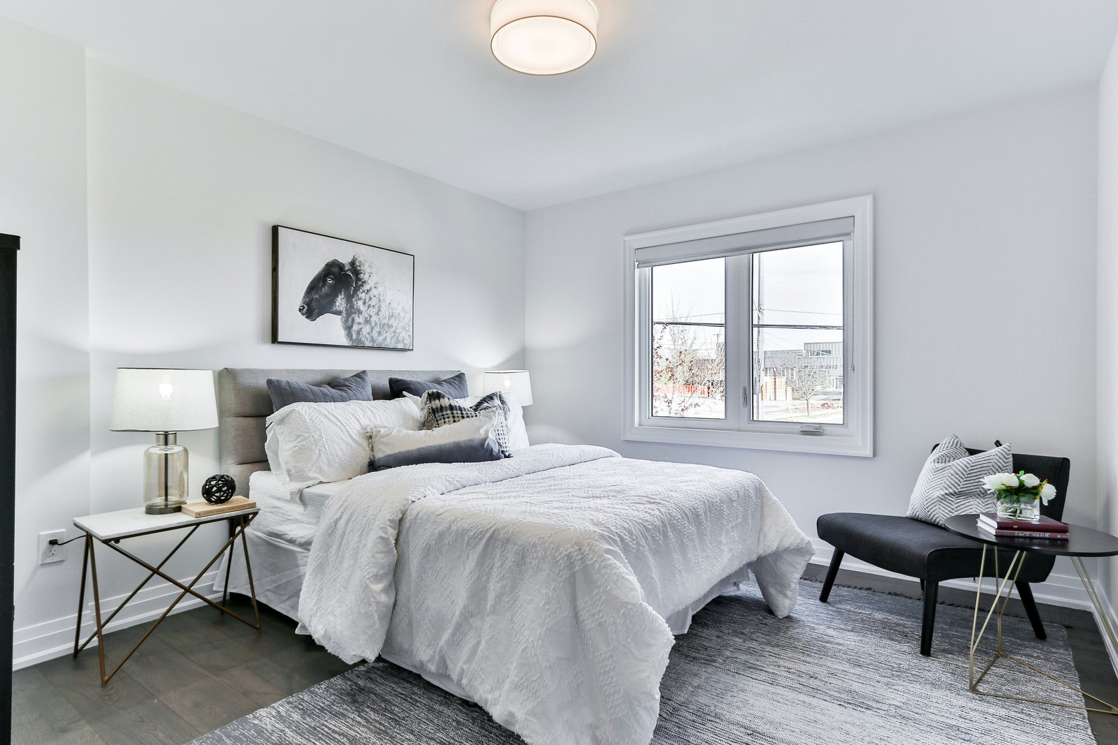 Bright neutral bedroom with textured white bedding, grey upholstered headboard and brass side table
